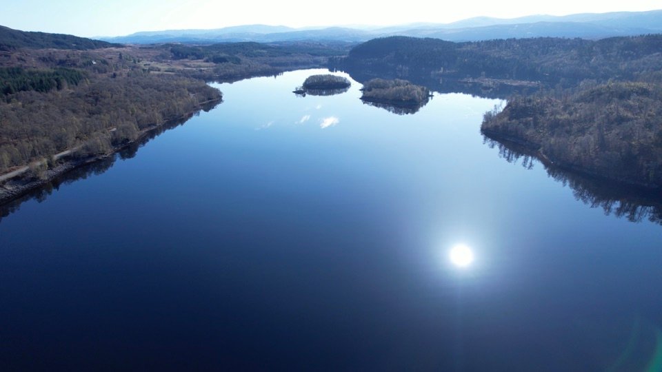 Aerial view across the water and forested shores of Loch Laggan.