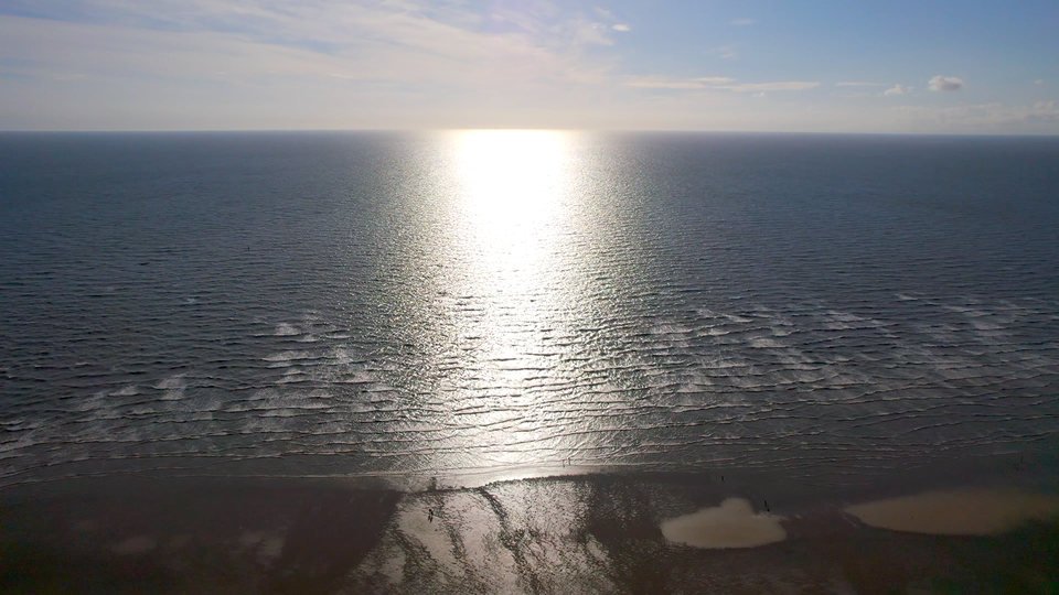 A low sun casts a long reflection across an open sea.